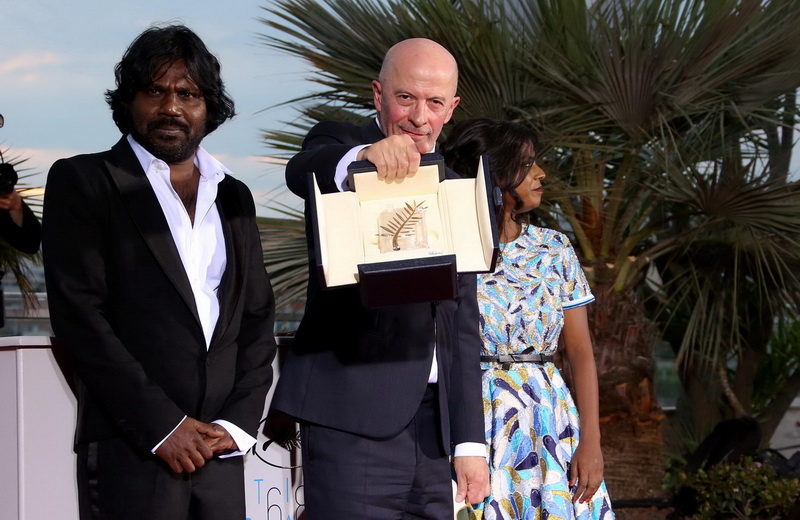 Entouré des acteurs Antonythasan Jesuthasan et Kalieaswari Srinivasan, Jacques Audiard brandit la Palme d'or qu'il a reçu pour son film 