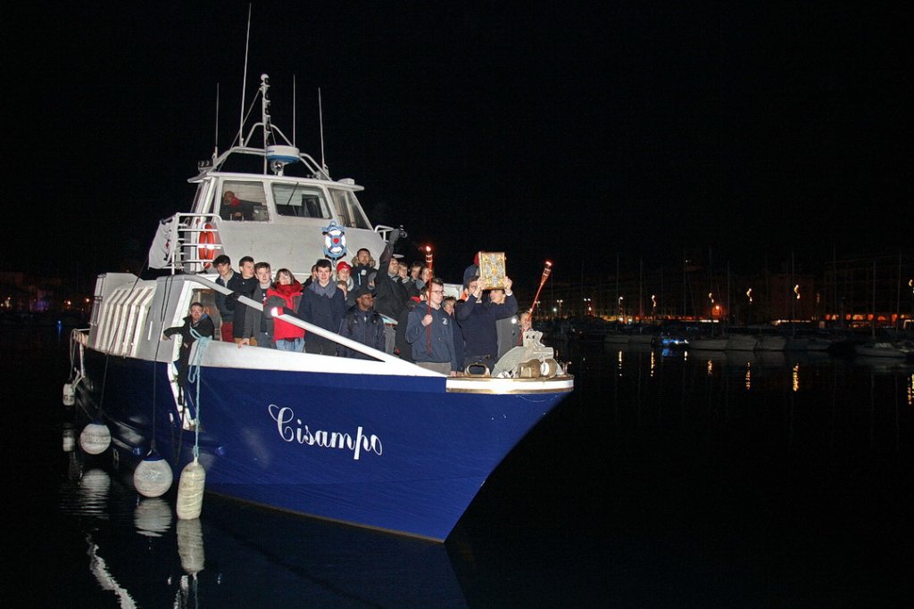 L’arrivée de l’Évangile par la mer transporté en bateau par les étudiants de la Marine Marchande avec à son bord Mgr Pontier Mgr Aveline (Photo Robert Poulain)