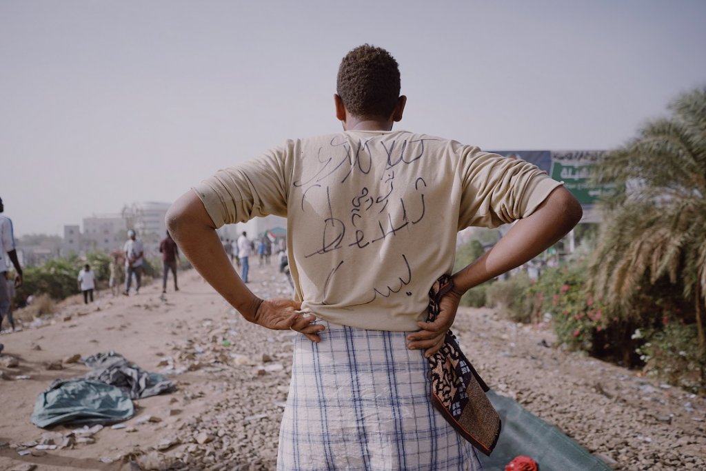 Cat 15 : Muhammad Salah. Un manifestant dont l'inscription au dos de sa chemise signifie « Un révolutionnaire de Kalakla, que la dictature tombe ! » ; il se tient sur la ligne ferroviaire centrale de Khartoum qui faisait partie de la zone de sit-in du QG de l'armée. Khartoum, Soudan, 13 avril 2019. Cat 15 : Muhammad Salah. Un manifestant dont l'inscription au dos de sa chemise signifie « Un révolutionnaire de Kalakla, que la dictature tombe ! » ; il se tient sur la ligne ferroviaire centrale de Khartoum qui faisait partie de la zone de sit-in du QG de l'armée. Khartoum, Soudan, 13 avril 2019.