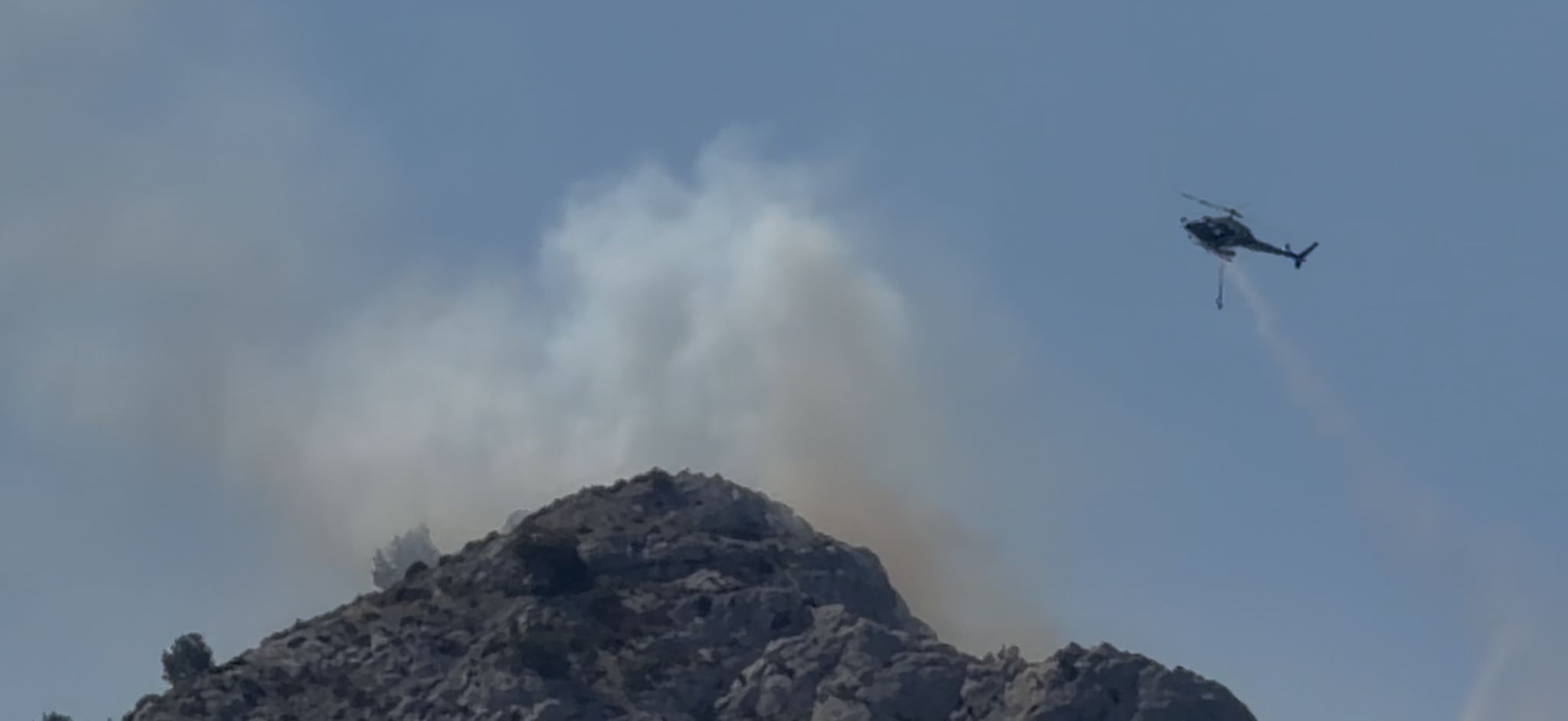 Un hélicoptère bombardier d’eau largue sa charge sur la reprise de feu dans le massif de Marseilleveyre, au cœur du parc national des Calanques (Photo Joël Barcy)